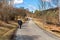 Lonely woman walks along a country asphalt road. Nordic walking. Walking for weight loss. Healthy movement