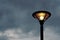 A lonely yellow light bulb on a classic lamp post on a beautiful gray cloud background inThailand