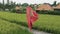 A lonely young dancer walks along the rice terrace in a red long silk dress, dances, raises her flowing skirt, which