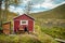 Lonely young man sitting in front of a red cabin in autumn