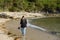 Lonely young woman in jeans walks barefoot on the beach