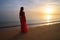 Lonely young woman standing on ocean beach by seaside enjoying warm tropical evening