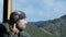 Lonesome bearded man standing on observation deck looking on a mountain and drinking coffee or tea from big cup. 4K