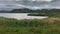 Long angle view: calm lake in front of low hills under clouds. Teriberka, Russia