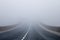 Long asphalt road in the fog