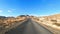 Long asphalt road and travel car movement point of view with outdoors beautiful sand desert around and blue sky in background.