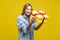 Long awaited present. Portrait of curious woman looking inside gift box. studio shot  on yellow background