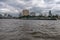 A long barge sails on the Chao Phraya River in downtown Bangkok, Thailand against a dramatic sky