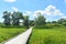 Long boardwalk through green meadow on a clear sunshiney day