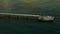 A long bridge over the sea. The view from the drone. Creative. A blue undulating sea with a long bridge over it where