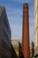 Long brown clay brick round chimney at dusk.