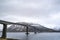 A long concrete bridge for cars and trucks crossing sea under cloudy sky.