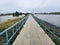 Long concrete pathway with blue metal barrier in the middle of nature with big ponds,