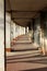 Long concrete pillars hallway supporting top floor and large entrance doors on side mounted on cracked floor of abandoned