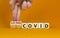 Long covid symbol. Doctor turnes wooden cubes and changes words `covid` to `long covid`. Beautiful orange background, copy spa