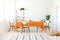 Long dining room table covered with orange tablecloth and comfortable white chairs