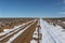 Long dirt road with snow cutting through open high desert in rural New Mexico