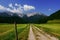 Long dirt road to wonderful high mountains while hiking at sunny weather