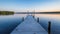 a long dock extends into the water at sunset or dawn