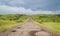 Long driveway in hills, storm landscape with clouds