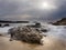 Long exposure of beautiful scene of waves on the coast with nice horizon and cloudy sky at sunset.