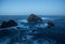 Long exposure during blue hour at Cabo Prior Lighthouse of waves crashing against steep rocky cliffs shore Galicia Spain