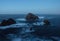 Long exposure during blue hour at Cabo Prior Lighthouse of waves crashing against steep rocky cliffs shore Galicia Spain