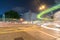 Long exposure captures light trails from passing and turning traffic in dark night urban street scene