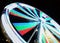 Long exposure motion blur of a spinning ferris wheel at night illuminated in bright neon colors