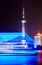 long exposure night shot of a blue illuminated boat on huangpu river passing the oriental pearl tower