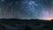 A long exposure photograph of the desert at night with the stars leaving trails of light across the sky. The stillness