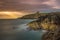 Long exposure of Scottish coastline with Dunskey castle in the background and sun rays on the cliffs.