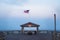 A long exposure of a shelter at the end of a pier with an American flag.