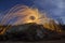 Long exposure shot of man standing on rocky hill spinning steel