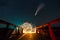 Long exposure of spinning steel wool in abstract circle making firework showers of yellow glowing sparks on a bridge with dark