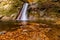 Long exposure view of the beautiful Pruncea Casoca Waterfall with fallen leaves in an autumn landscape