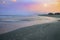 A long exposure of waves on the pink sand at Holly Beach, Louisiana, at sunset