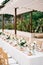 Long festive table in the garden under a canopy with small pomegranates on plates