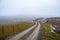 Long foggy and creepy road surrounded by hills covered in greens