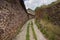 Long grassy pathway surrounded by rocky walls under the cloudy sky