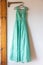 long green bridesmaid dress with embroidery and sequins is on a hanger on the wall
