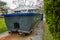 A long green empty dumpster full of debris is seen in the driveway in front of a home being renovated