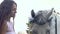 Long-haired bride in white wedding dress is posing near horse