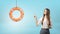 A long-haired businesswoman points to a small orange life buoy hanging from a rope.