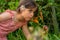 Long-haired Colombian girl smells the flowers of the garden in the spring