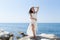 Long-haired girl in wedding dress posing on stone barefoot