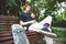 Long-haired hipster skater in a cap sits on a bench and spins on a spin-spinner