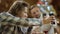 Long haired man showing his smartphone screen to his grandmother by Christmas family table