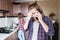 A long-haired man is upset talking on the phone or calling a food and drug delivery service home standing in the kitchen