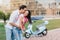 Long-haired smiling girl in ripped blue jeans having fun with boyfriend in city park. Outdoor portrait of funny loving